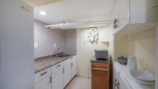 kitchen featuring white cabinets, sink, tasteful backsplash, and light tile patterned flooring