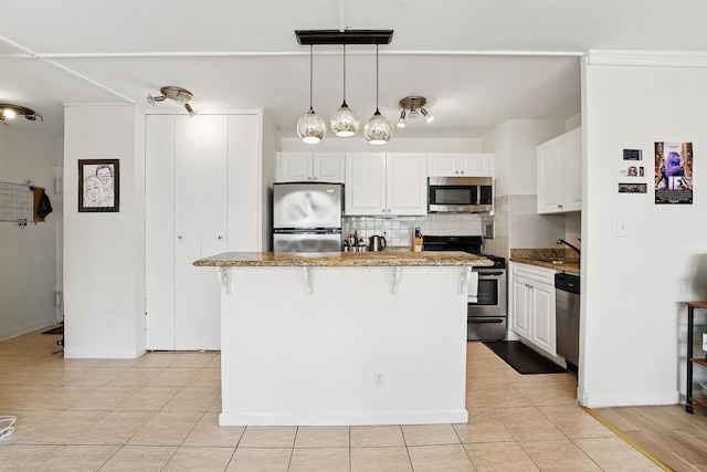 kitchen with white cabinets, a kitchen breakfast bar, stainless steel appliances, a center island, and decorative backsplash