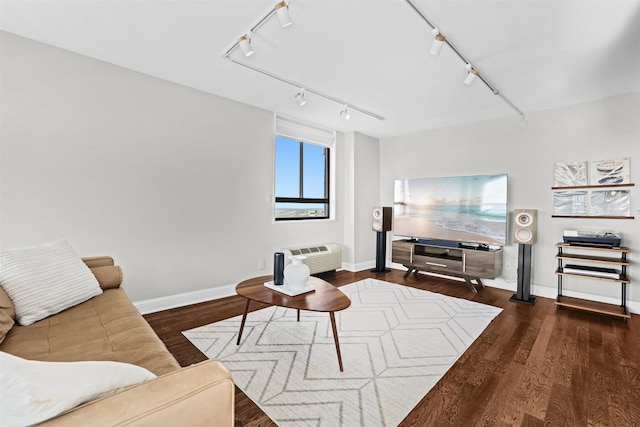 living room featuring baseboards, a wall unit AC, wood finished floors, and track lighting