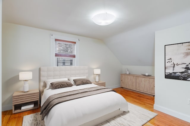 bedroom featuring vaulted ceiling, light wood finished floors, and baseboards