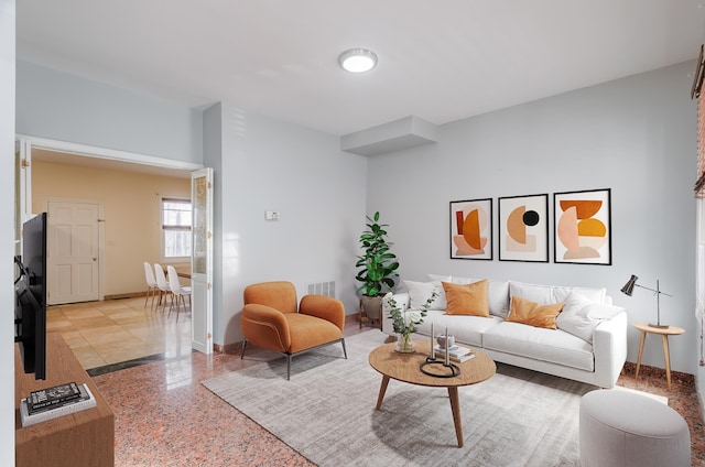 living area with baseboards, visible vents, and speckled floor