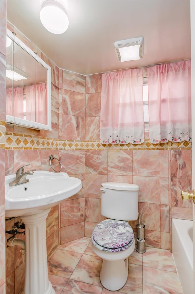 full bathroom featuring a bath, toilet, and tile walls