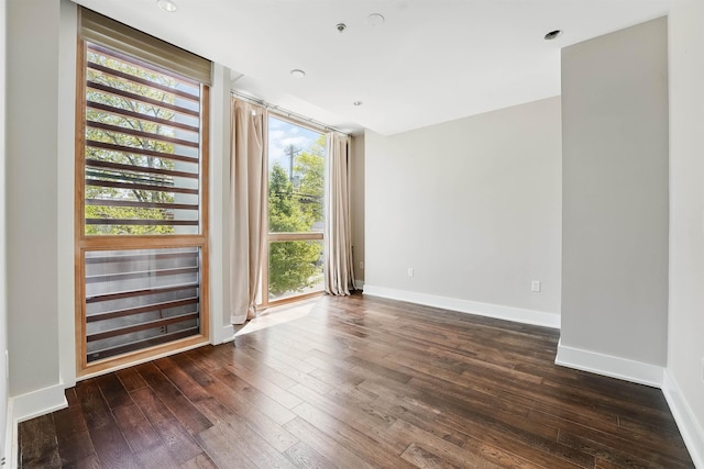 unfurnished room featuring baseboards and dark wood-style floors