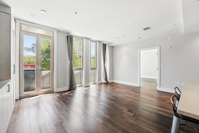unfurnished living room featuring french doors, baseboards, wood finished floors, and visible vents