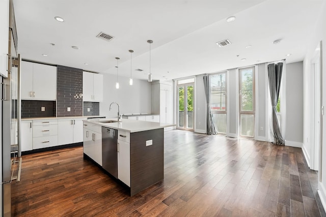 kitchen with a sink, dishwasher, tasteful backsplash, visible vents, and a center island with sink