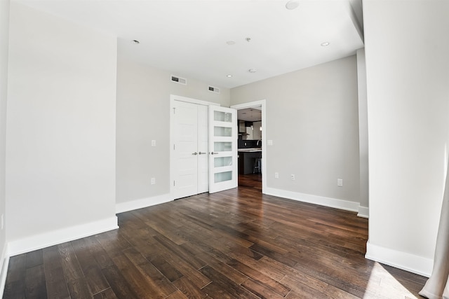 unfurnished bedroom with visible vents, baseboards, and dark wood-style floors
