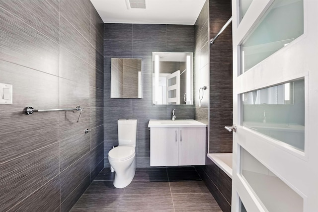 bathroom featuring toilet, tile patterned floors, tile walls, and vanity