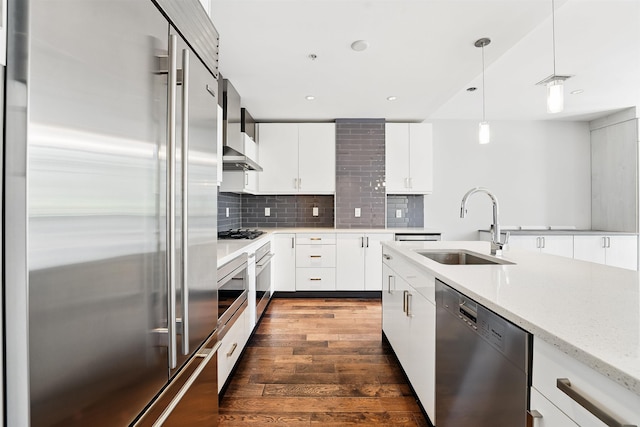 kitchen with dark wood-style flooring, decorative light fixtures, tasteful backsplash, a sink, and stainless steel appliances