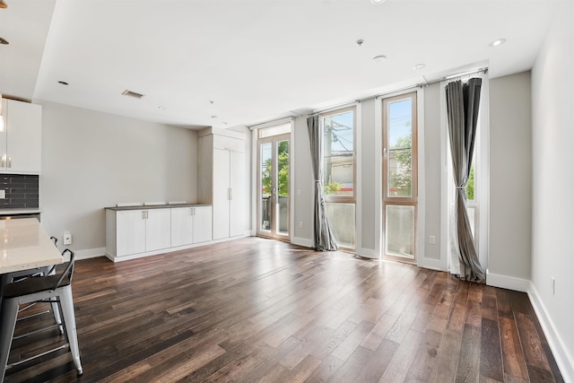 unfurnished living room with recessed lighting, baseboards, dark wood-style floors, and visible vents