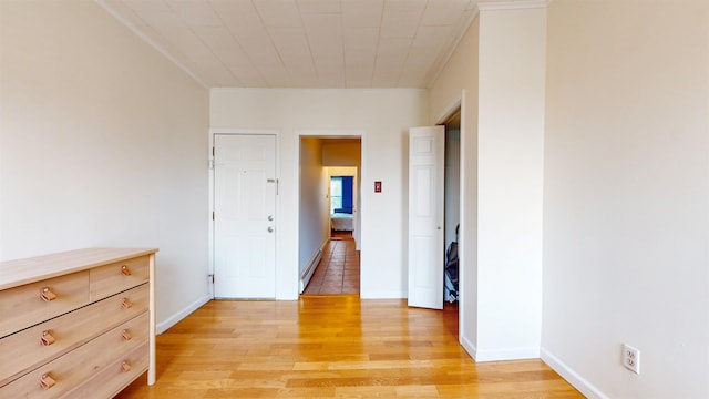 hall with a baseboard heating unit, light hardwood / wood-style floors, and crown molding