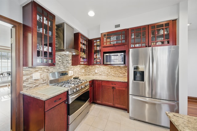 kitchen with visible vents, tasteful backsplash, stainless steel appliances, reddish brown cabinets, and wall chimney range hood