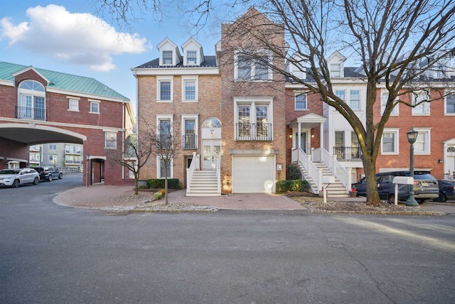 view of property featuring a garage, brick siding, and driveway