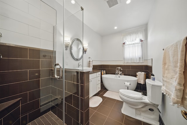 bathroom with visible vents, a stall shower, tile patterned floors, a soaking tub, and tile walls