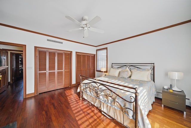 bedroom with visible vents, ornamental molding, multiple closets, and wood finished floors