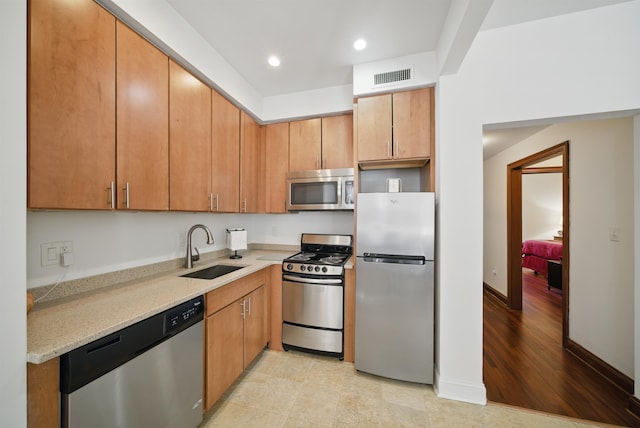 kitchen with visible vents, a sink, light stone counters, recessed lighting, and stainless steel appliances