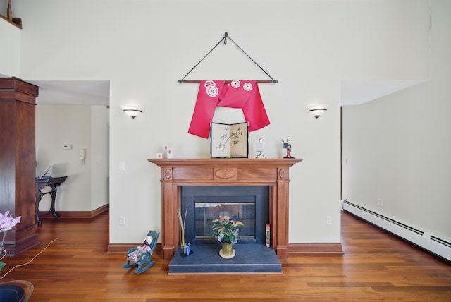 living area with a glass covered fireplace, wood finished floors, baseboards, and a baseboard radiator