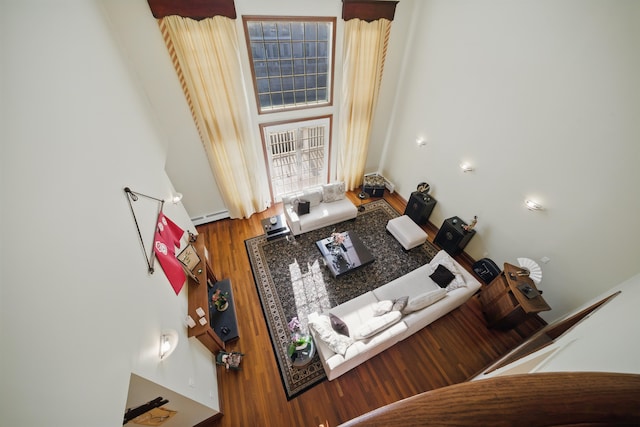 living area with plenty of natural light, baseboard heating, and wood finished floors