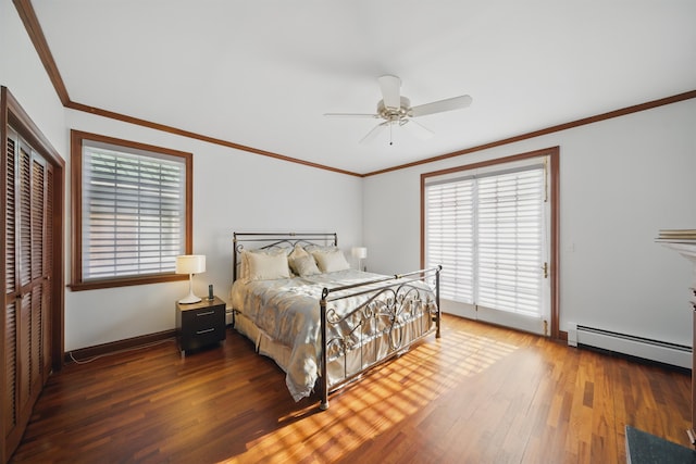 bedroom featuring crown molding, a baseboard heating unit, baseboards, wood finished floors, and a closet