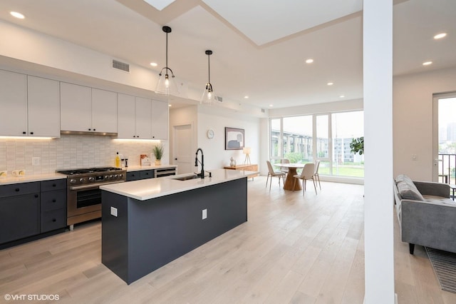 425 3rd St Unit 404, Jersey City, NJ 07302 - kitchen with stainless steel range, open floor plan, light countertops, light wood finished floors, and decorative backsplash