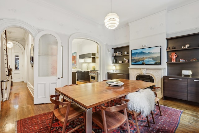 dining area with built in features, hardwood / wood-style flooring, and ornamental molding