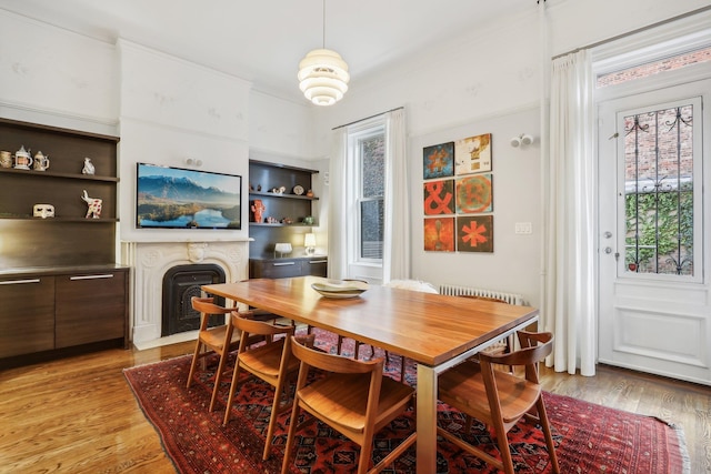 dining area featuring radiator, light wood-type flooring, and built in shelves