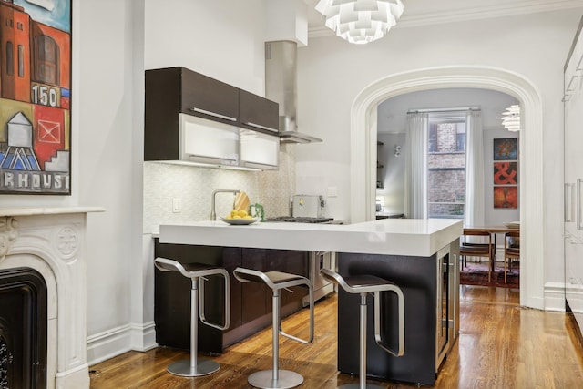 kitchen featuring dark hardwood / wood-style flooring, range hood, kitchen peninsula, and a kitchen bar