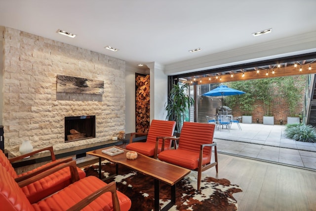 living room featuring ornamental molding, a healthy amount of sunlight, hardwood / wood-style flooring, and an outdoor stone fireplace