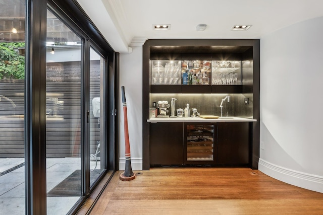 bar with light hardwood / wood-style floors, wine cooler, and crown molding