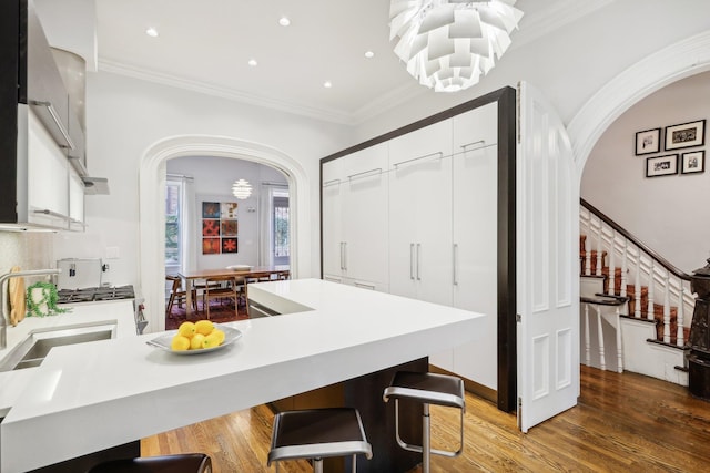 kitchen with wood-type flooring, white cabinetry, a breakfast bar, and a kitchen island