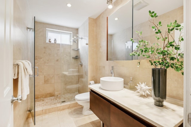 bathroom featuring tile walls, walk in shower, vanity, tile patterned flooring, and toilet