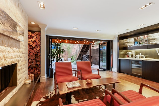 interior space featuring a fireplace, hardwood / wood-style flooring, crown molding, and wine cooler