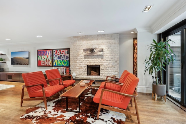 living room featuring a stone fireplace, light wood-type flooring, and crown molding