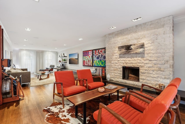 living room with hardwood / wood-style flooring, a stone fireplace, and crown molding