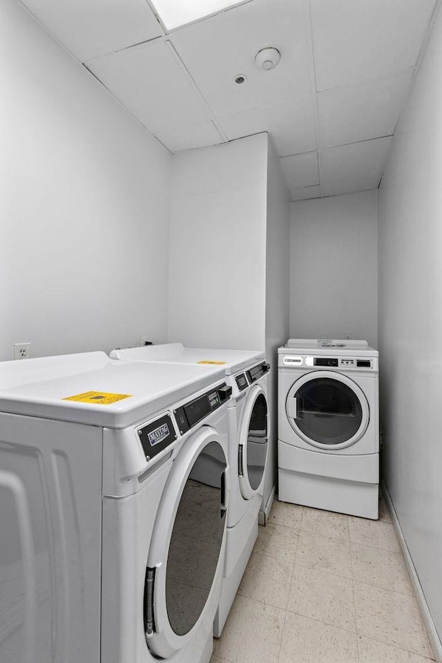laundry area with washer and dryer, baseboards, and light floors