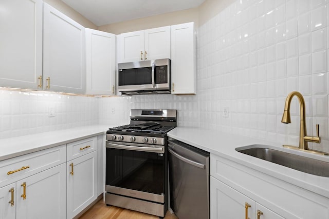 kitchen with a sink, tasteful backsplash, stainless steel appliances, and white cabinetry
