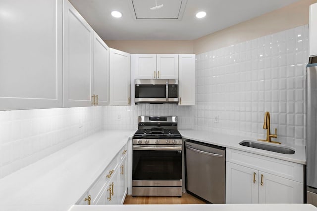 kitchen featuring light countertops, white cabinetry, a sink, appliances with stainless steel finishes, and backsplash