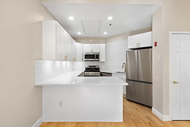 kitchen with light countertops, appliances with stainless steel finishes, decorative backsplash, and a sink
