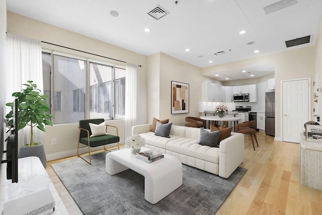 living room featuring recessed lighting, visible vents, and light wood finished floors