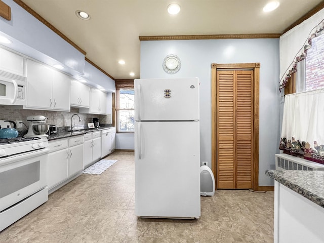 kitchen with sink, white cabinets, dark stone counters, ornamental molding, and white appliances