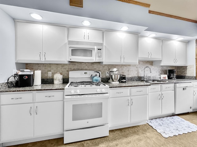 kitchen with sink, white appliances, dark stone countertops, backsplash, and white cabinets