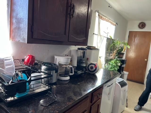 kitchen featuring dark brown cabinets and dark stone countertops