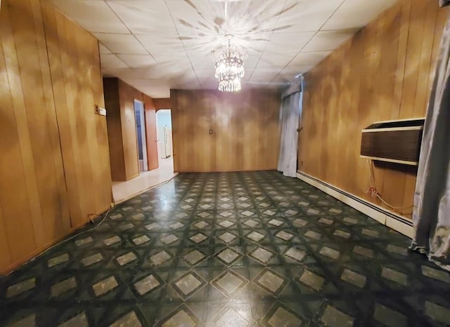 interior space featuring wooden walls, a baseboard radiator, tile patterned floors, a wall mounted air conditioner, and a chandelier