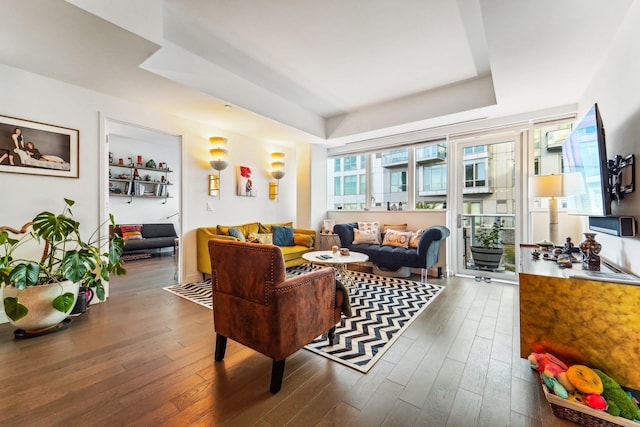 living area featuring a tray ceiling and dark wood finished floors