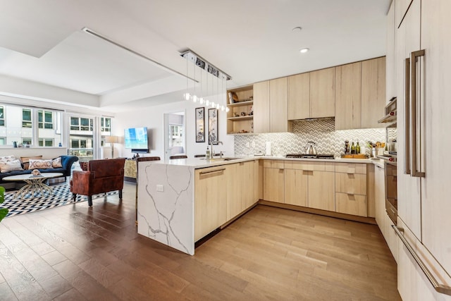 kitchen with light brown cabinetry, sink, light wood-type flooring, and kitchen peninsula