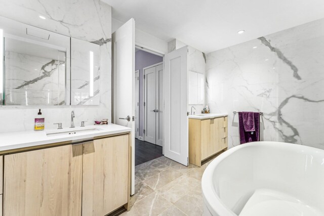 bathroom featuring vanity, a bathtub, and tile walls