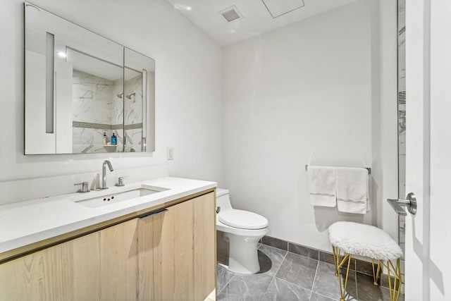 bathroom with vanity, toilet, and a tile shower