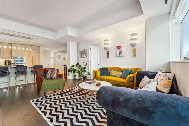 living room with a raised ceiling and dark wood-style floors