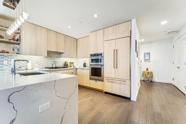 kitchen with a sink, light brown cabinets, modern cabinets, and built in fridge