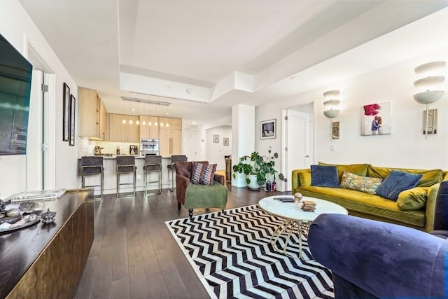 living room featuring a tray ceiling and dark hardwood / wood-style floors