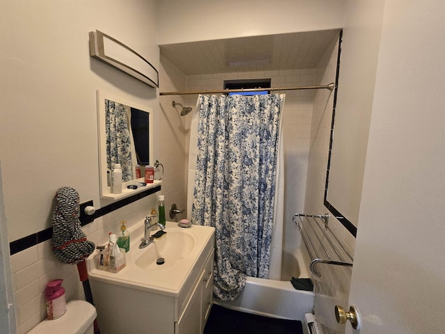 full bathroom featuring vanity, shower / bath combination with curtain, toilet, and tile walls